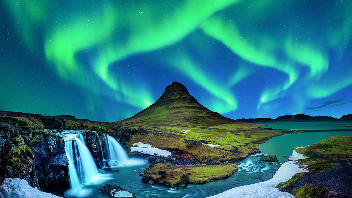 Northern lights glowing above an Icelandic waterfall